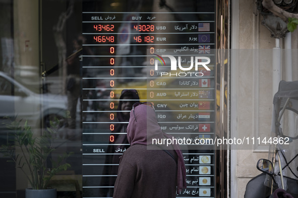 An Iranian woman is looking at an electronic board displayed at a currency exchange shop in Tehran's business district, in Tehran, Iran, on...