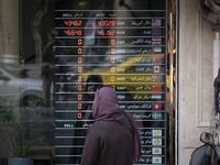 An Iranian woman is looking at an electronic board displayed at a currency exchange shop in Tehran's business district, in Tehran, Iran, on...