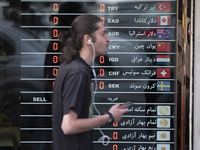 A young Iranian man is walking past an electronic board displayed at a currency exchange shop in Tehran's business district, Iran, on April...