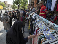 An elderly Iranian woman, veiled, is looking at dresses while shopping from a vendor near the Grand Bazaar in southern Tehran, Iran, on Apri...