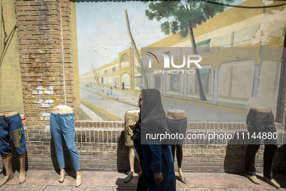 An Iranian woman is walking past mannequins placed on a sidewalk near the Grand Bazaar in southern Tehran, Iran, on April 13, 2024. Meanwhil...