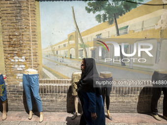 An Iranian woman is walking past mannequins placed on a sidewalk near the Grand Bazaar in southern Tehran, Iran, on April 13, 2024. Meanwhil...