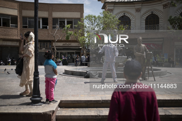 An Iranian street artist is performing on a sidewalk near the Grand Bazaar in southern Tehran, Iran, on April 13, 2024. Meanwhile, the Prime...