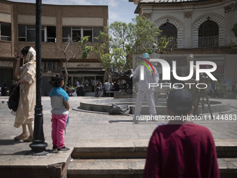 An Iranian street artist is performing on a sidewalk near the Grand Bazaar in southern Tehran, Iran, on April 13, 2024. Meanwhile, the Prime...