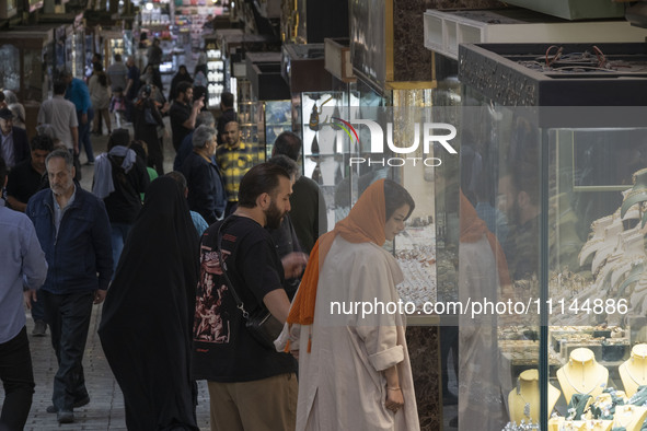 An Iranian couple is looking at a gold shop window while shopping at the Grand Bazaar in southern Tehran, Iran, on April 13, 2024. Meanwhile...