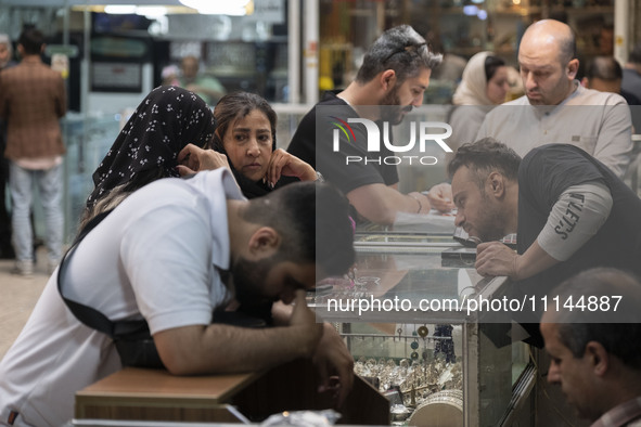 Two Iranian women are speaking with each other while shopping at the Grand Bazaar in southern Tehran, Iran, on April 13, 2024. Meanwhile, th...