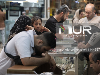 Two Iranian women are speaking with each other while shopping at the Grand Bazaar in southern Tehran, Iran, on April 13, 2024. Meanwhile, th...