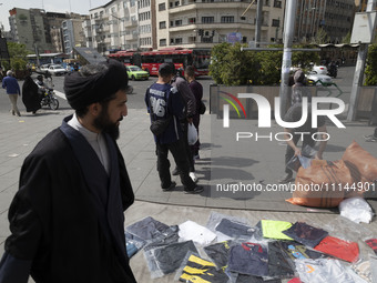 An Iranian cleric is walking past a vendor on a sidewalk in downtown Tehran, Iran, on April 13, 2024. Meanwhile, the Prime Minister of Israe...