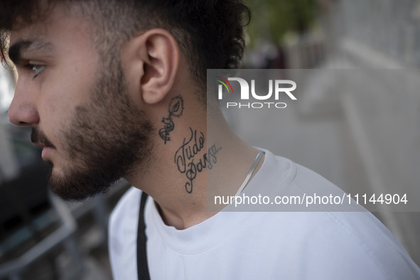 An Iranian art student, who has a tattoo on his neck, is standing on a sidewalk in downtown Tehran, Iran, on April 13, 2024. Meanwhile, the...