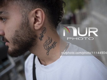 An Iranian art student, who has a tattoo on his neck, is standing on a sidewalk in downtown Tehran, Iran, on April 13, 2024. Meanwhile, the...