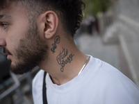 An Iranian art student, who has a tattoo on his neck, is standing on a sidewalk in downtown Tehran, Iran, on April 13, 2024. Meanwhile, the...