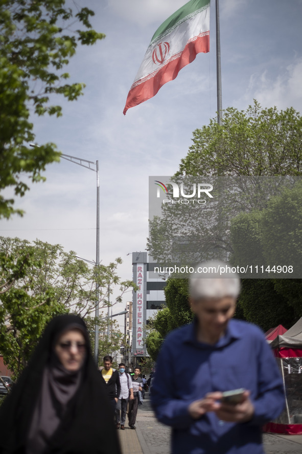 People in Tehran, Iran, are walking under a massive Iranian flag in downtown on April 13, 2024. The Prime Minister of Israel, Benjamin Netan...