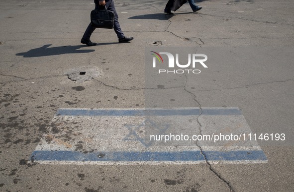 People are walking past an Israeli flag in downtown Tehran, Iran, on April 14, 2024. Iran is launching dozens of Unmanned Aerial Vehicles (U...