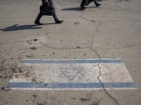 People are walking past an Israeli flag in downtown Tehran, Iran, on April 14, 2024. Iran is launching dozens of Unmanned Aerial Vehicles (U...