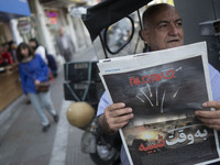 An Iranian man is sitting on a sidewalk in downtown Tehran, Iran, on April 14, 2024, holding a Jam-e Jam daily newspaper that features an il...