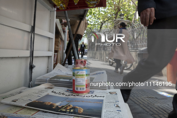 An Iranian man is walking past a Jam-e Jam daily newspaper featuring an image of Iranian surface-to-surface missiles on its front page in do...