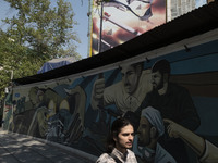 A young Iranian man is walking under an anti-Israeli mural, which celebrates the IRGC missile and UAV attack on Israel, in downtown Tehran,...