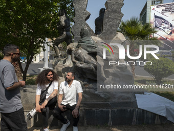 Young Iranian men are sitting and talking near an anti-Israeli mural that appreciates the IRGC missile and UAV attack on Israel, in downtown...