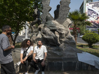 Young Iranian men are sitting and talking near an anti-Israeli mural that appreciates the IRGC missile and UAV attack on Israel, in downtown...