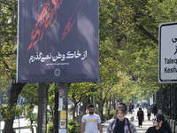 Two young Iranian women, who are not wearing mandatory headscarves, are walking past a billboard with Persian script that reads, ''I will no...