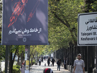 A young Iranian woman is walking past a billboard with Persian script that reads, ''I will not leave my homeland,'' which is illustrated to...