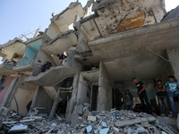 Palestinians are inspecting the damage to a building following Israeli bombardment in the Maghazi camp for Palestinian refugees in the centr...