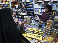 An Iranian woman, her face veiled, is shopping at a supermarket and standing next to an anti-Israeli placard as she participates in a celebr...