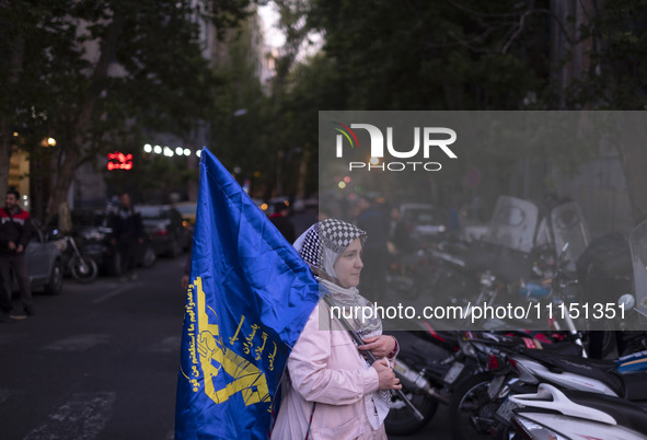 An Iranian woman is carrying a flag of the Islamic Revolutionary Guard Corps while attending a gathering to celebrate the IRGC UAV and missi...