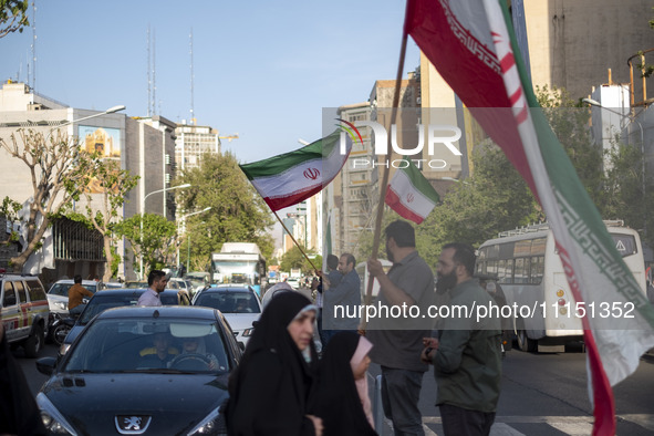 Men are waving Iranian flags during a gathering to celebrate the IRGC UAV and missile attack against Israel, in Tehran, Iran, on April 15, 2...