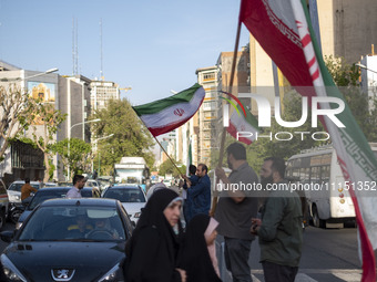 Men are waving Iranian flags during a gathering to celebrate the IRGC UAV and missile attack against Israel, in Tehran, Iran, on April 15, 2...