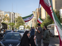 Men are waving Iranian flags during a gathering to celebrate the IRGC UAV and missile attack against Israel, in Tehran, Iran, on April 15, 2...