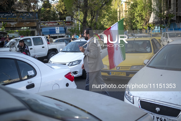 A man is carrying an Iranian flag during a gathering to celebrate the IRGC UAV and missile attack against Israel, in Tehran, Iran, on April...