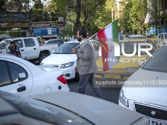 A man is carrying an Iranian flag during a gathering to celebrate the IRGC UAV and missile attack against Israel, in Tehran, Iran, on April...