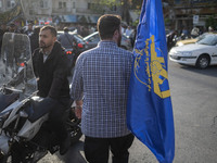 An Iranian man is carrying a flag of the Islamic Revolutionary Guard Corps during a gathering to celebrate the IRGC UAV and missile attack a...