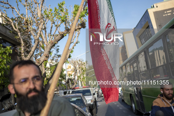 A man is carrying an Iranian flag during a gathering to celebrate the IRGC UAV and missile attack against Israel, at Palestine Square in dow...