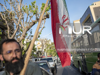 A man is carrying an Iranian flag during a gathering to celebrate the IRGC UAV and missile attack against Israel, at Palestine Square in dow...