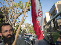 A man is carrying an Iranian flag during a gathering to celebrate the IRGC UAV and missile attack against Israel, at Palestine Square in dow...