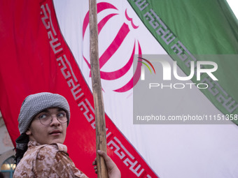 An Islamic Revolutionary Guard Corps military personnel is holding a massive Iranian flag during a gathering to celebrate the IRGC UAV and m...