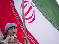 An Islamic Revolutionary Guard Corps military personnel is holding a massive Iranian flag during a gathering to celebrate the IRGC UAV and m...