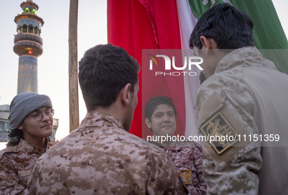 Islamic Revolutionary Guard Corps military personnel are standing together next to a massive Iranian flag during a gathering to celebrate th...