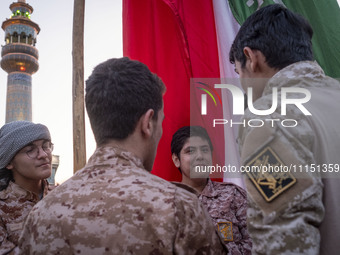 Islamic Revolutionary Guard Corps military personnel are standing together next to a massive Iranian flag during a gathering to celebrate th...