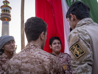 Islamic Revolutionary Guard Corps military personnel are standing together next to a massive Iranian flag during a gathering to celebrate th...