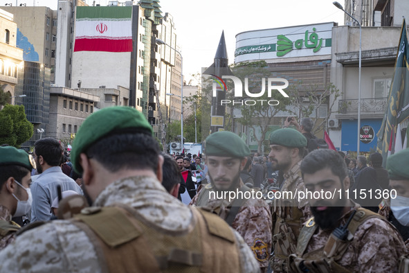 Members of the Islamic Revolutionary Guard Corps (IRGC) Special Forces are standing together under a model of Iran's first-ever hypersonic m...