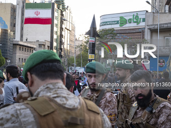 Members of the Islamic Revolutionary Guard Corps (IRGC) Special Forces are standing together under a model of Iran's first-ever hypersonic m...