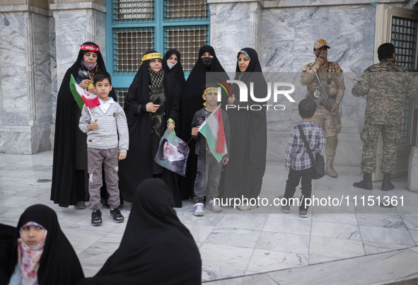 An armed member of the Islamic Revolutionary Guard Corps (IRGC) is speaking on a walkie-talkie and monitoring an area during a celebration o...