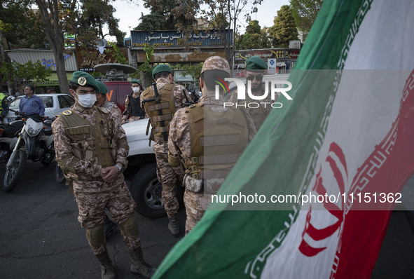 Members of the Islamic Revolutionary Guard Corps (IRGC) Special Forces are standing together behind an Iranian flag during a celebration of...