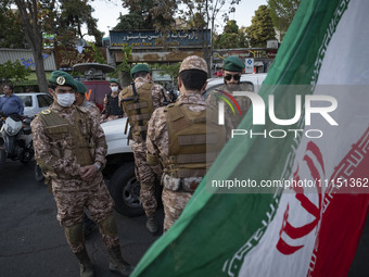 Members of the Islamic Revolutionary Guard Corps (IRGC) Special Forces are standing together behind an Iranian flag during a celebration of...