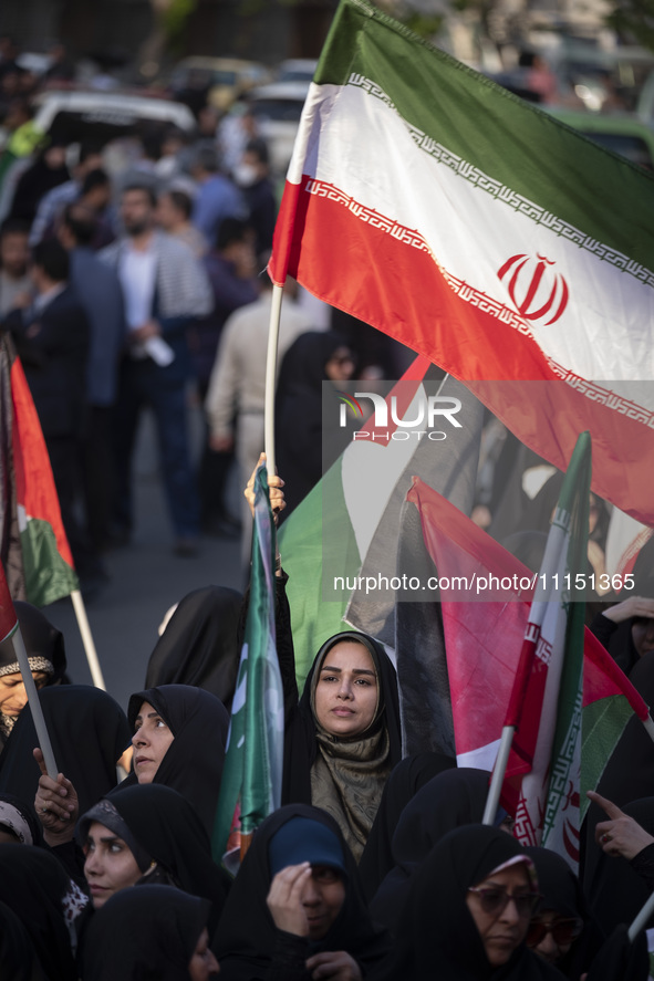 A veiled woman is waving an Iranian flag while participating in a gathering to celebrate the IRGC UAV and missile attack against Israel, in...