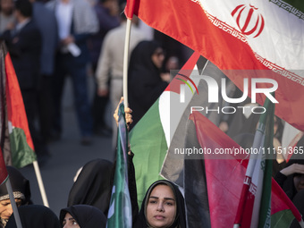 A veiled woman is waving an Iranian flag while participating in a gathering to celebrate the IRGC UAV and missile attack against Israel, in...