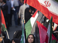 A veiled woman is waving an Iranian flag while participating in a gathering to celebrate the IRGC UAV and missile attack against Israel, in...